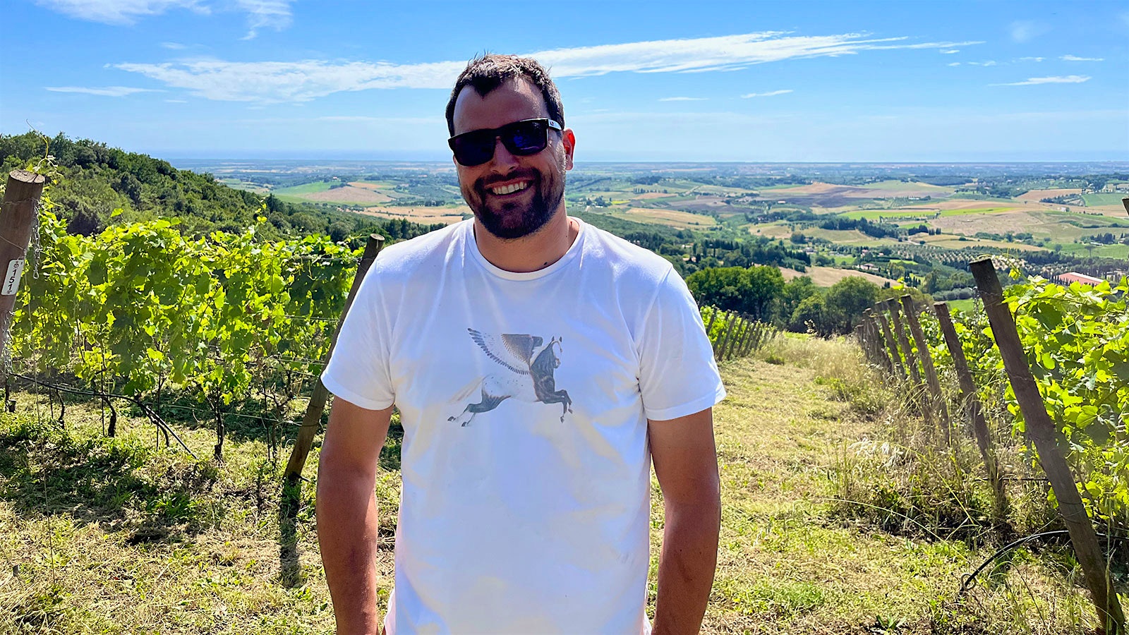Rocco Toscani wearing sunglasses and smiling in one of Toscani's vineyards in Tuscany